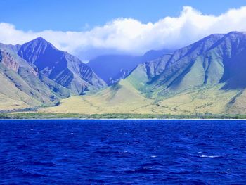 Scenic view of sea and mountains against blue sky