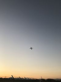 Low angle view of silhouette airplane against clear sky