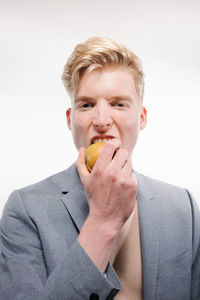 Portrait of man holding ice cream against white background