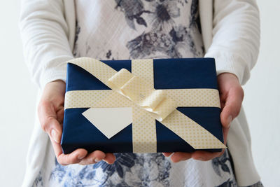 Midsection of woman holding gift against white background