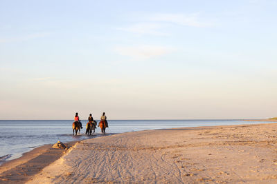 Three women horseback riding on beach