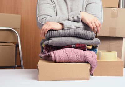 Woman in a gray sweater is packing clothes in a box, the concept of assistance and volunteerin