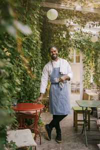 Smiling male owner standing near table outside restaurant