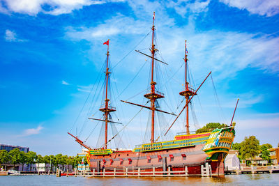 Sailboats moored at harbor against sky