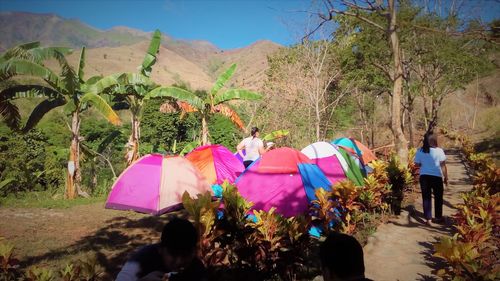 People walking in tent on landscape against sky