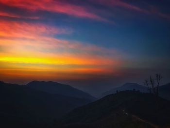 Scenic view of silhouette mountains against orange sky