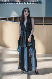 Portrait of woman standing against wall