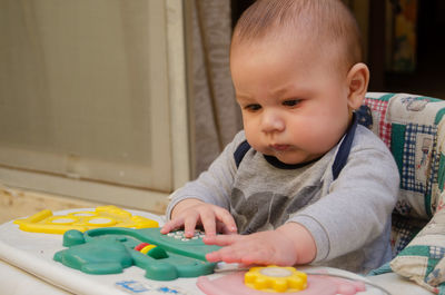 Cute baby boy looking away while playing with toys at home