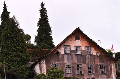 Low angle view of trees and building against sky