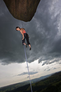 Female rock climber descending cliff at the peak district in england