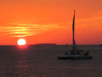 Sailboat sailing on sea against orange sky
