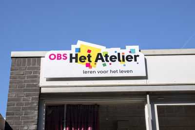 Low angle view of information sign against clear blue sky