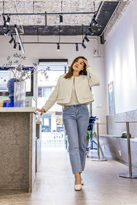 Full length portrait of young woman standing against ceiling