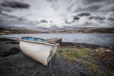 Boat moored on beach against sky