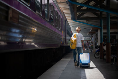 Rear view of man standing on railroad station platform