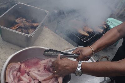 Close-up of man preparing food on barbecue grill