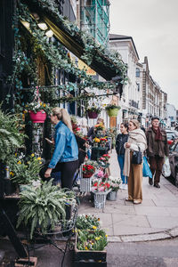 People on street amidst plants in city