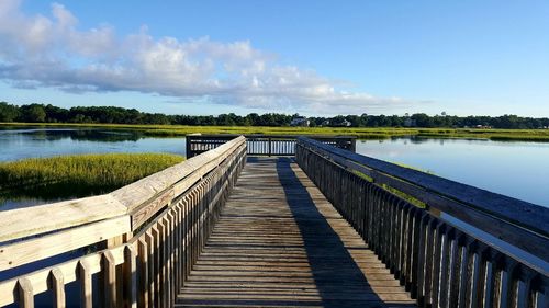 Pier over lake against cloudy sky