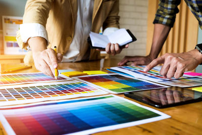 Midsection of design professionals working over color swatch on table