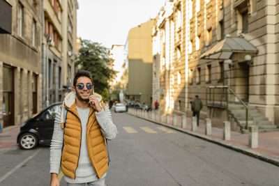 Portrait of smiling young woman using phone while standing on street