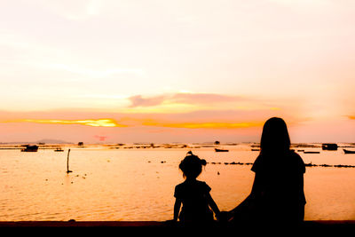 Silhouette people on beach against sky during sunset