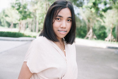 Portrait of young woman standing against trees