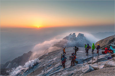 People on mountain against sky during sunset