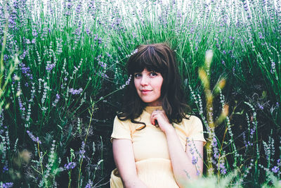 Portrait of beautiful young woman standing by flowering plants