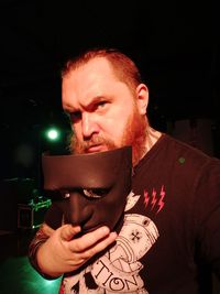 Portrait of young man holding camera at night