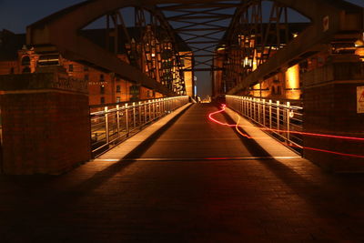 Light trails on bridge amidst buildings at night
