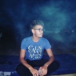 Man sitting amidst smoke at night