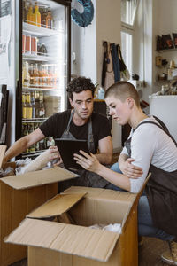 Male and female business owners doing inventory through tablet pc at cafe