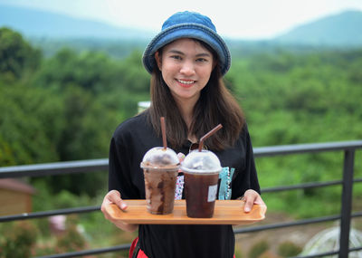 Portrait of smiling young woman holding drink