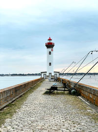 Lighthouse by sea against sky