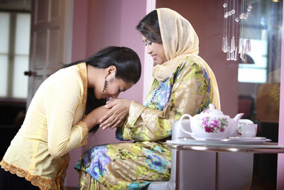 Side view of mother and daughter holding hands at home