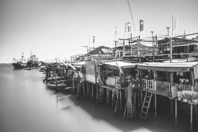 Boats moored at harbor against clear sky