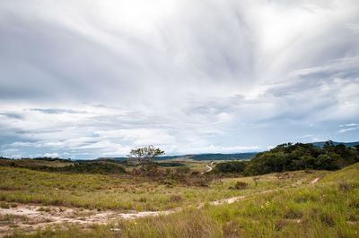 Scenic view of grassy field against cloudy sky