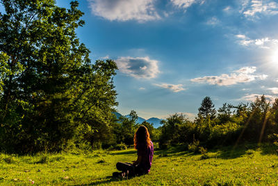 Man sitting on field against sky