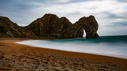 Rock formation on beach against sky
