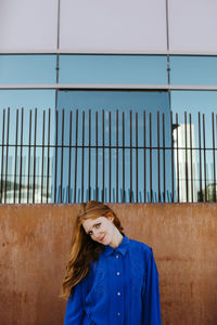 Portrait of woman standing against blue wall