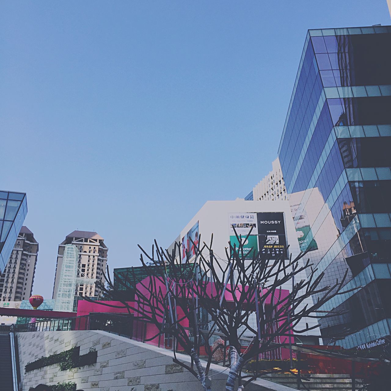 building exterior, architecture, built structure, clear sky, low angle view, blue, city, building, copy space, text, day, tower, outdoors, communication, western script, no people, sunlight, tree, residential building, residential structure