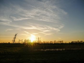 Electricity pylon on field against sky during sunset