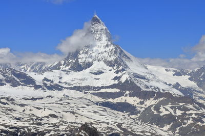 Scenic view of snowcapped mountains against blue sky