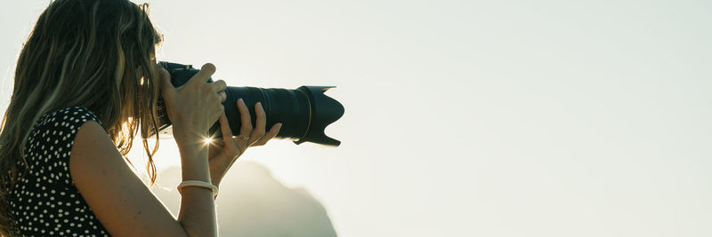 Woman photographing against clear sky