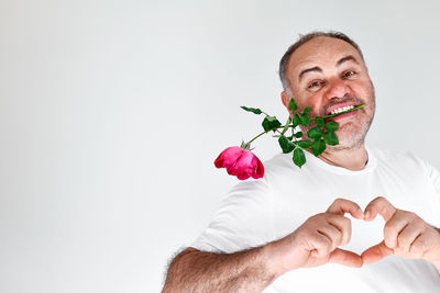 Portrait of man holding rose against white background