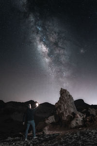 Rear view of man standing on mountain against sky at night