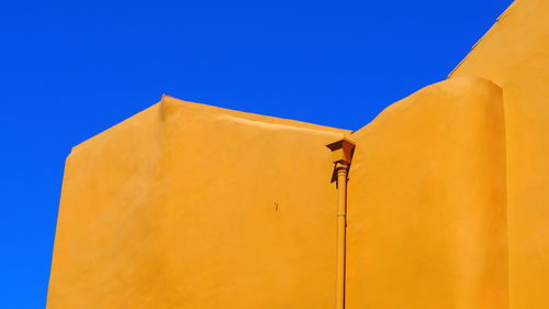 Low angle view of yellow building against blue sky