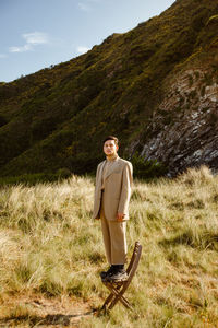 Young ethnic male model in stylish suit looking at camera on sunny day in countryside