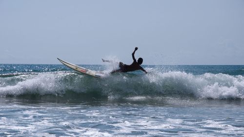 Surfer surfing on sea against sky