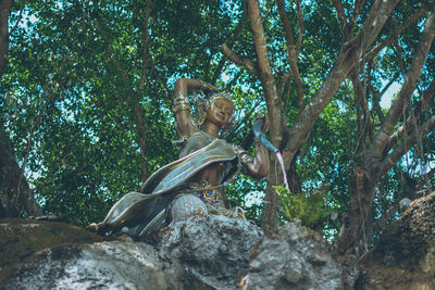 Low angle view of statue against trees in forest